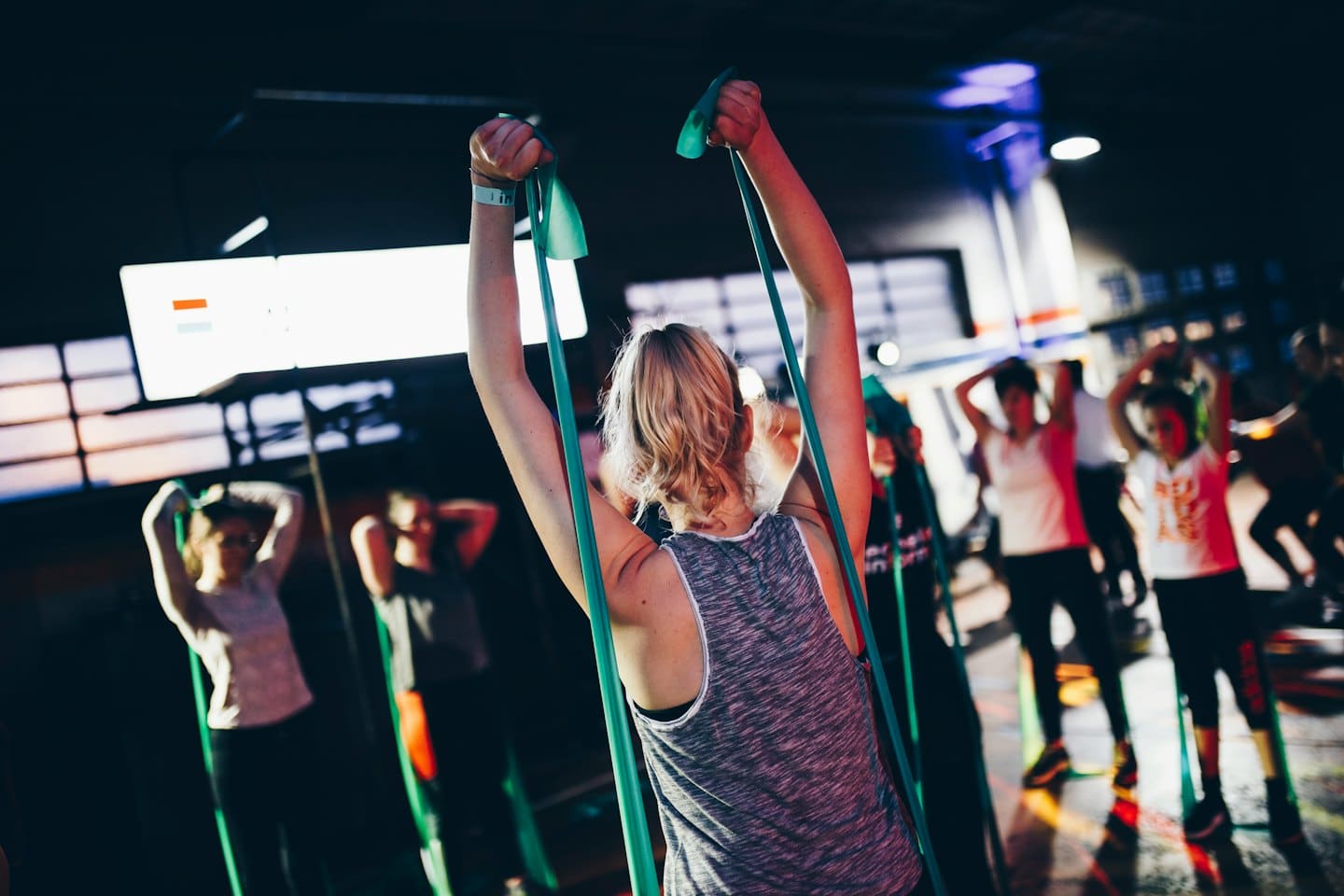 People exercising with green resistance bands in a fitness studio.